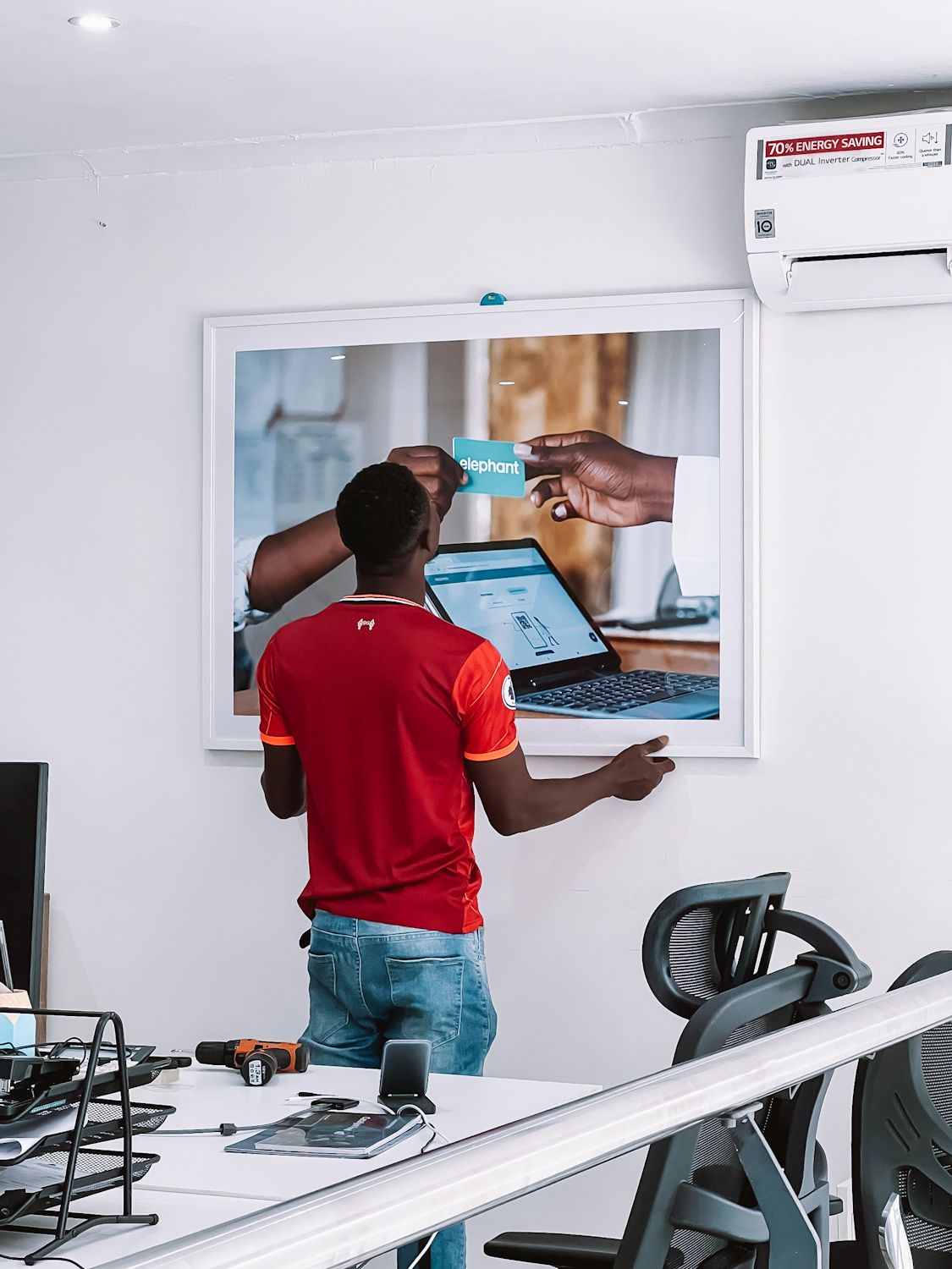 A professional framegidi frame installer adjusting frames hung on the wall for perfect display.