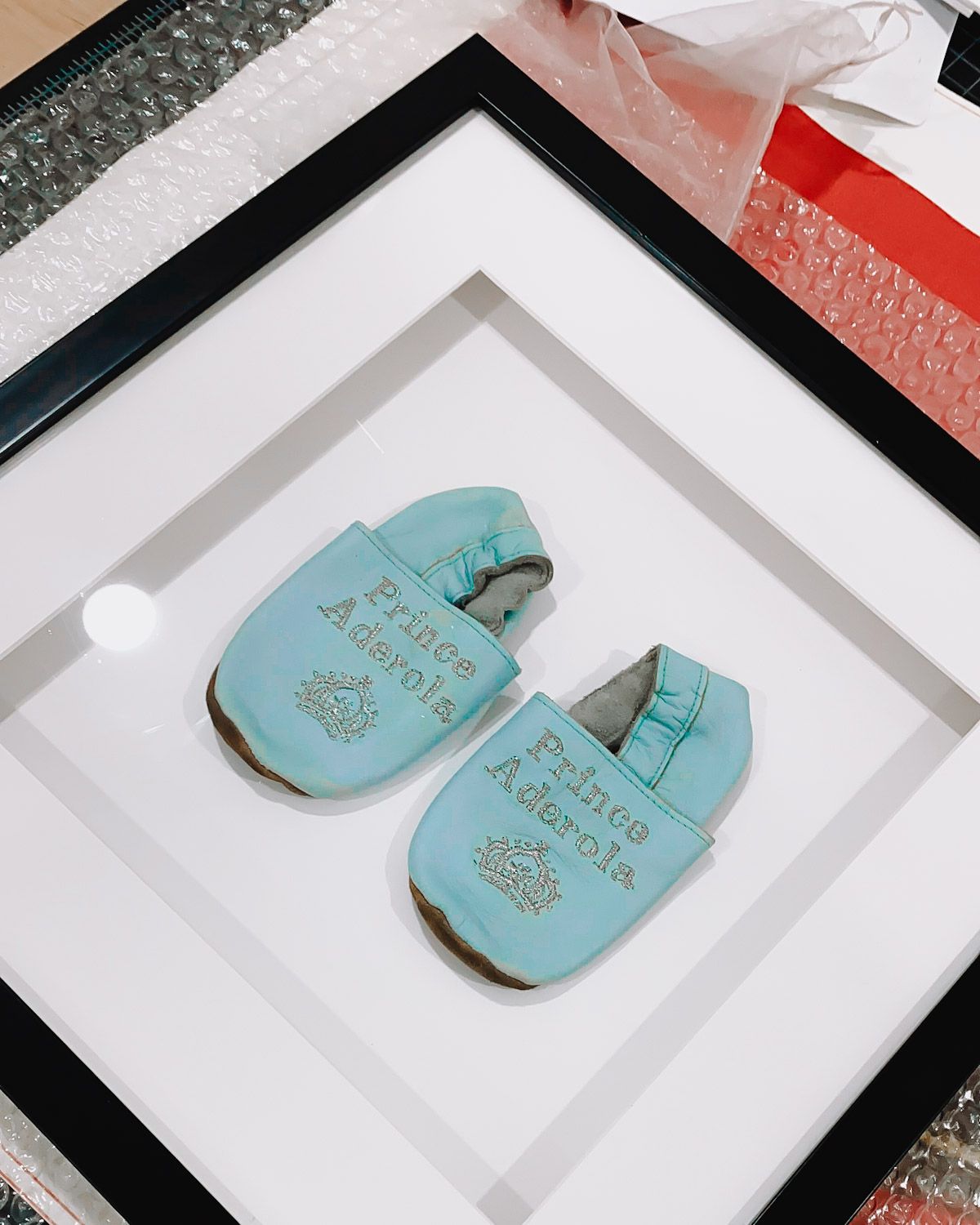 Pair of blue baby shoes in a matted frame