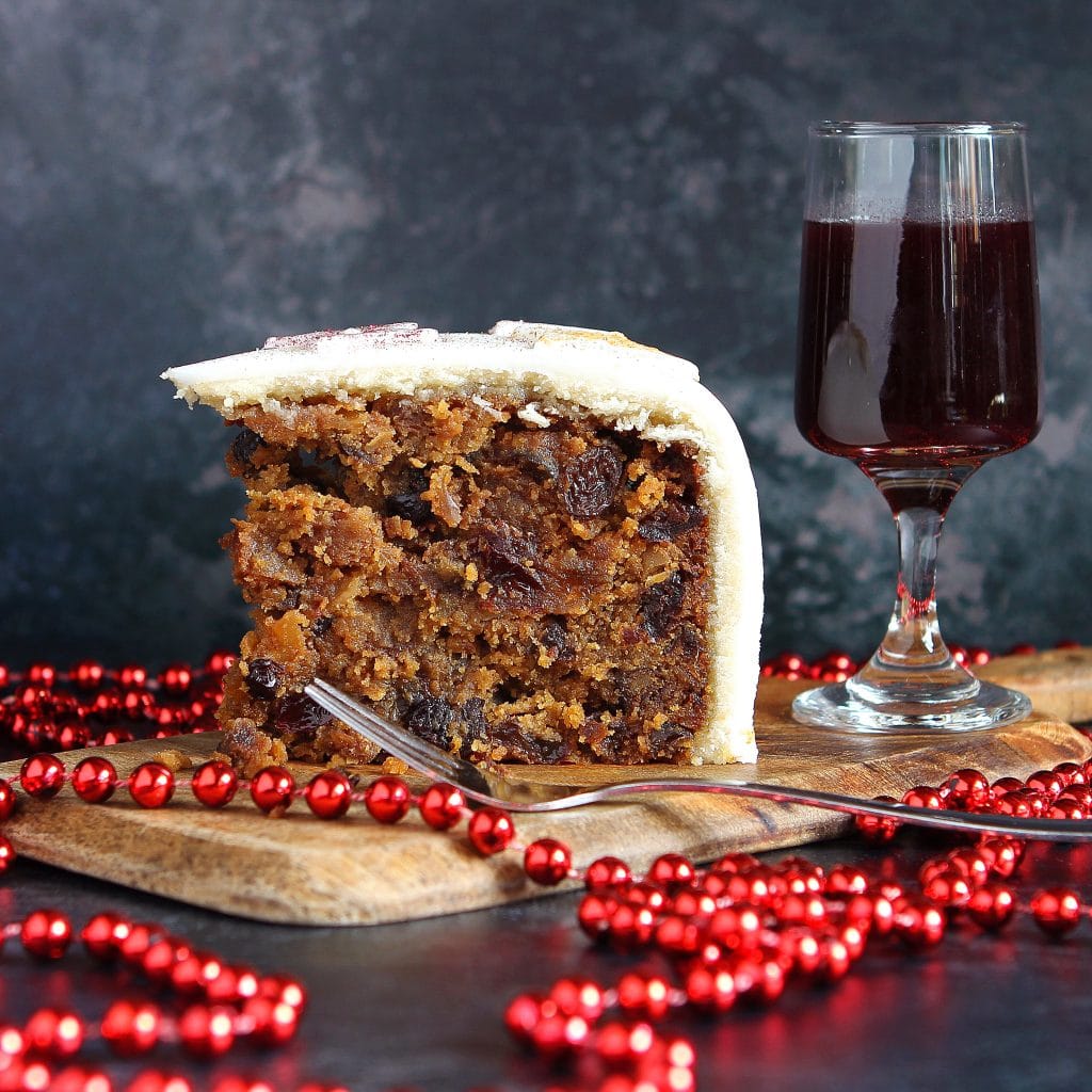 Slice of fruit cake with a glass of red wine on a wooden tray