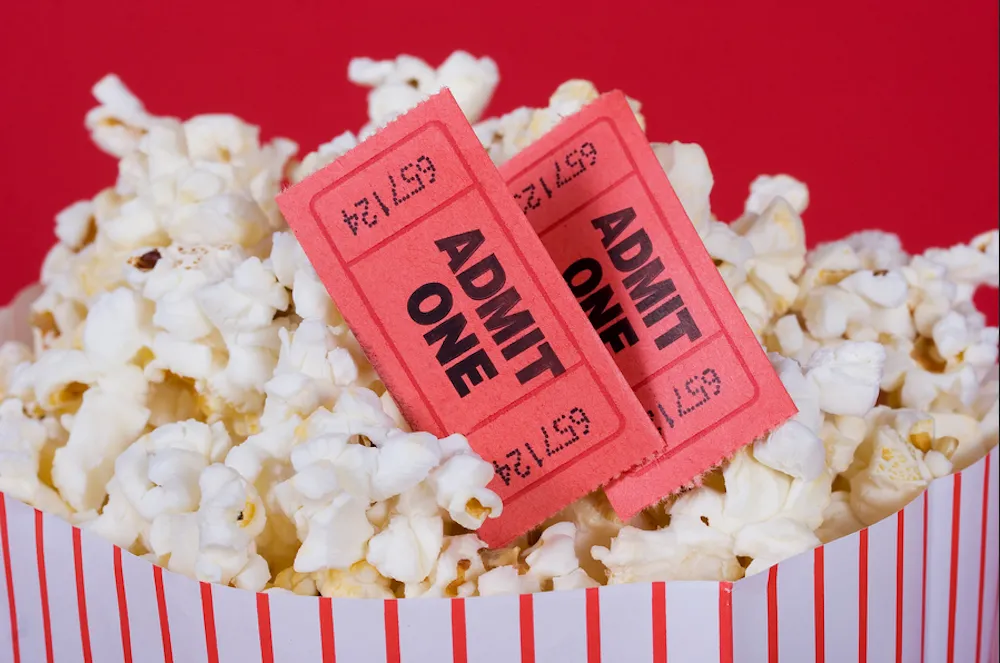 Two movie tickets in a bowl of popcorn